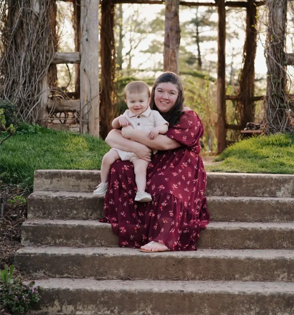 Amber Mio smiling on stone steps holding Brayden