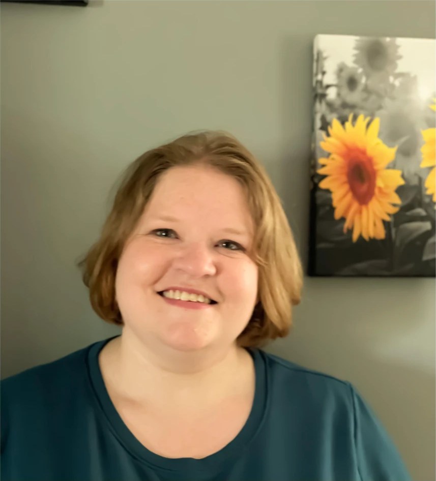 Lisa Huggard smiling in front of a sunflower painting