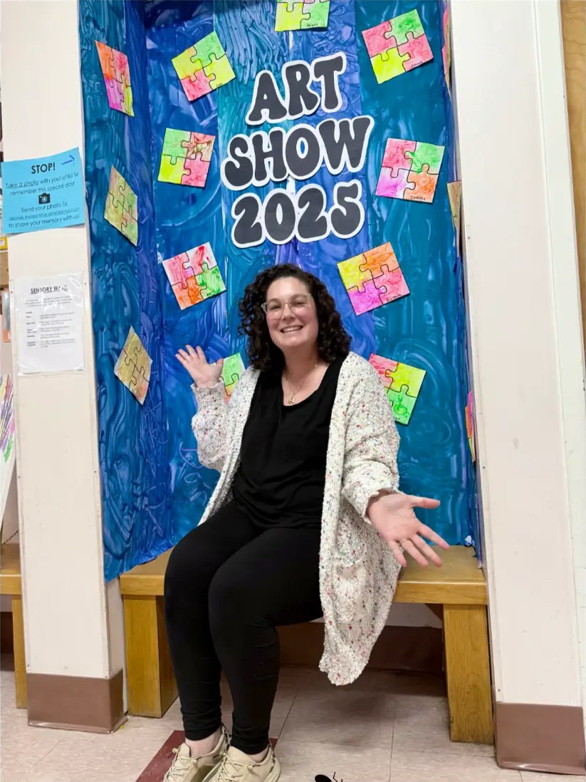 Alicia Power smiling in front of a colorful Art Show 2025 display