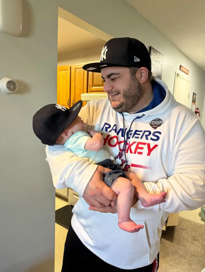 Giovanni Mio holding baby Brayden, both wearing Yankees caps